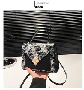 Detail of black and white snakeskin pattern patchwork crossbody bag with gold buckle
