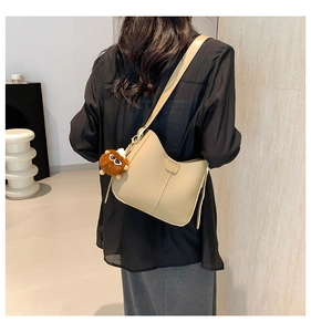 Detail of beige hobo shoulder bag with fashion embossing and brown plush charm