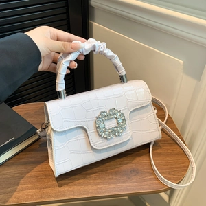 Sac à main blanc motif crocodile avec boucle strass et poignée plissée porté à la main