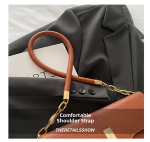 Detail of brown litchi pattern leather bag with gold chain and thick handle