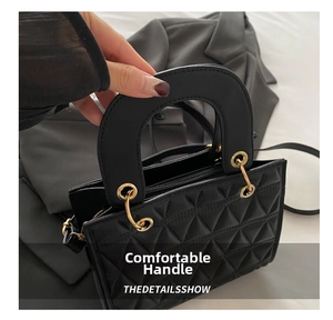 Detail of black quilted leather handbag with rigid handle and gold metal hardware