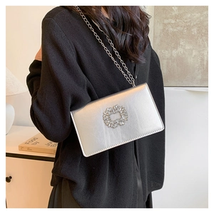 Détail du sac bandoulière argenté avec boucle en cristal et fine chaîne métallique