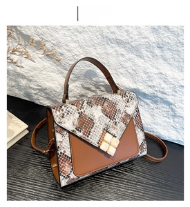 Detail view of coffee brown crossbody bag with snake skin pattern and gold clover lock