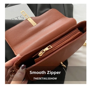 Detail shot of brown lychee grain leather handbag featuring a smooth gold zipper compartment