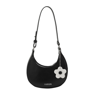 Minimalist black crescent shoulder bag with floral pendant and silver hardware accent