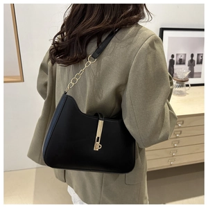 Chic black minimalist underarm bag with gold metal buckle shown on a model's shoulder