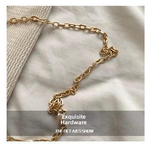 Close-up of polished gold metal chain link details on a leopard print clutch bag
