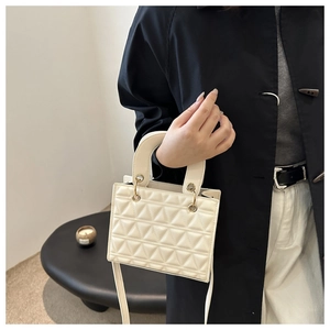 Detail of cream quilted handbag featuring elegant lattice stitching and gold hardware