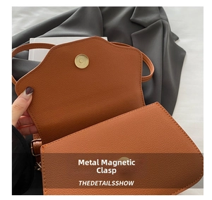 Detail of vintage gold magnetic clasp on brown lychee pattern leather shoulder bag