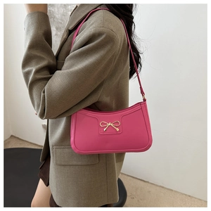 Dettaglio della borsa sottobraccio in pelle rosa con fibbia a fiocco dorata su blazer
