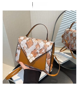 Detailed close-up of brown patchwork bag with snake print and clover-shaped lock