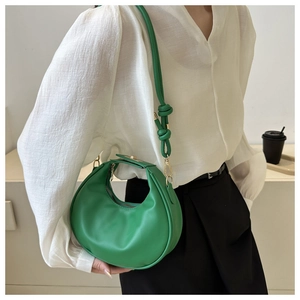 Detail of green crescent bag featuring unique knotted strap and gold hardware accents