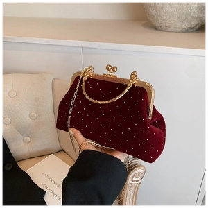 Gros plan d'un sac coquillage en velours bordeaux avec strass et chaîne dorée