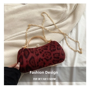 Detail of burgundy leopard print velvet clutch with gold chain and large pearl clasp