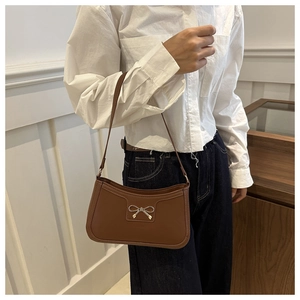 Dettaglio di una borsa baguette marrone vintage con elegante chiusura a fiocco dorato