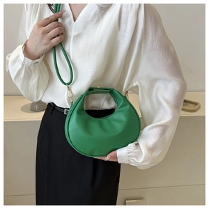 Detail of bright green crescent handbag with smooth leather texture and golden hardware