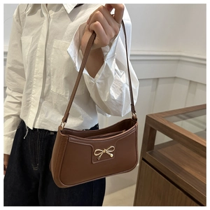 Dettaglio della borsa baguette marrone vintage con fibbia dorata a fiocco di tendenza