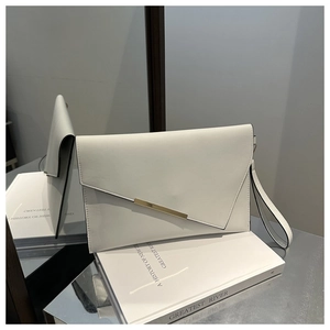 Detail of white envelope clutch with gold metal trim and black painted edges