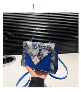 Detail view of the blue crossbody bag featuring snakeskin pattern and gold square lock