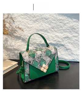 Detail of green crossbody bag with snakeskin texture flap and decorative white squares