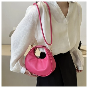 Detail of rose pink dumpling bag with gold hardware and removable shoulder strap