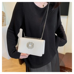 Détail d'un sac bandoulière en similicuir beige avec boucle en strass et chaîne argentée