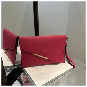 Detail of rose pink envelope clutch with V-shaped flap and gold metal trim on book