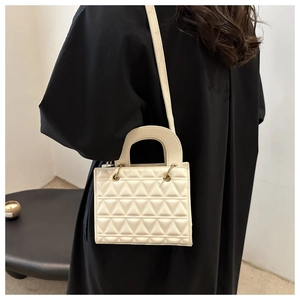 Detail of cream quilted handbag with triangle stitching and gold metal ring connectors