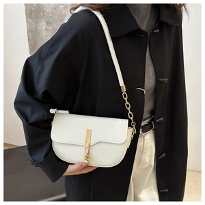 Close-up of white lychee leather saddle bag featuring gold bar buckle and chain strap
