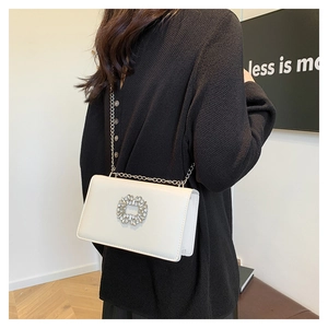 Gros plan d'un sac bandoulière blanc en cuir avec boucle en cristal et chaîne argentée