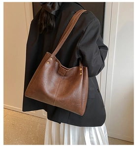 Gros plan sur un sac cabas en cuir marron avec rivets dorés et boucle de fermeture