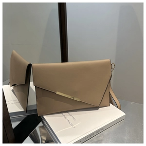 Detail of beige envelope clutch bag showing gold metal trim and leather strap texture