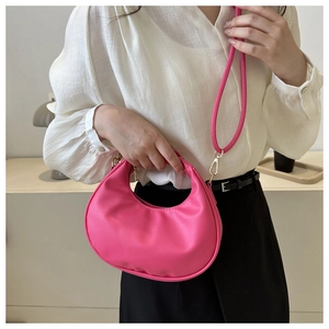 Pink crescent crossbody bag detail showing smooth faux leather texture and model styling