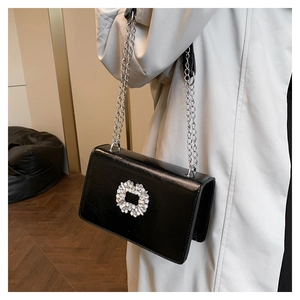Détail du sac carré noir de luxe avec boucle en cristal et bandoulière en chaîne