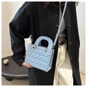 Detail of light blue quilted crossbody bag with golden metal hardware and strap
