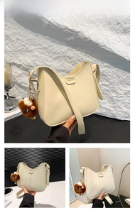 Detail view of off-white minimalist leather bucket bag with cute plush pendant accessory