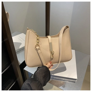 Close-up of beige crescent shoulder bag with gold chain and metal bar lock hardware