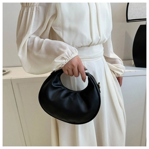 Detail of a black hobo bag with gold metal buckle shown on a white dress model