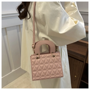 Detail of pink quilted handbag with triangular stitching and gold metal hardware