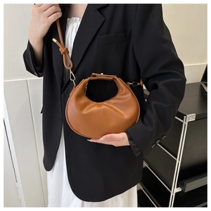 Brown vegan leather crescent bag with adjustable knot strap shown on a black blazer