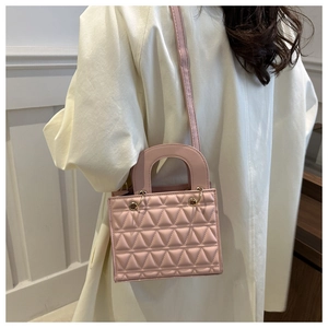 Detailed side view of a pink quilted handbag featuring a top handle and gold metal rings