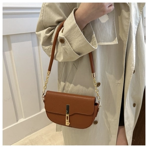 Brown lychee leather saddle bag with gold metal trim and chain strap shown on shoulder