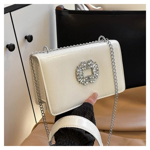 Détail du sac ivoire montrant la boucle en strass et la bandoulière en chaîne argent