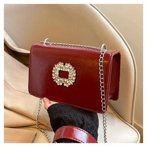 Gros plan du sac à chaîne rouge vin avec boucle en strass carrée et texture vintage