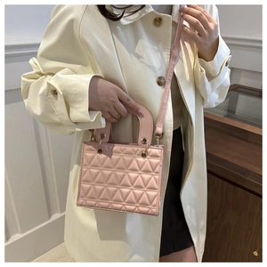 Close-up of pink quilted crossbody bag with unique triangular pattern and metal eyelets