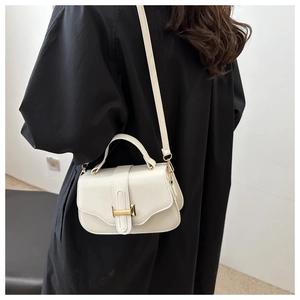 Close-up of white lychee leather texture and golden metal buckle on underarm bag