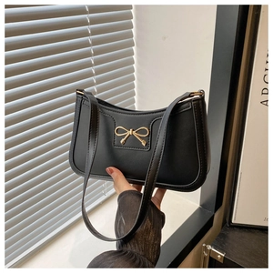 Close-up of black leather underarm bag with a vintage golden bow buckle and slim strap