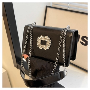 Détail du sac en cuir noir brillant avec boucle en strass et fine chaîne en argent