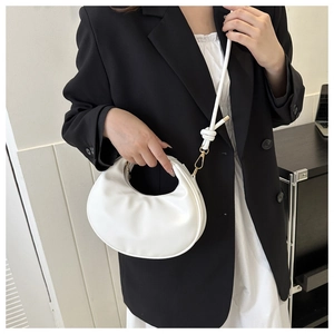 Detail view of a white half-moon bag featuring a knotted strap and golden hardware hooks