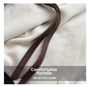 Gros plan des poignées en cuir marron grainé sur un grand sac cabas fourre-tout